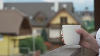 Yakındaki kadınlar, modern evlerin manzarası güzel olan ahşap balkonda çay ya da kahve içmek için beyaz bardak kaldırıyorlar. Kırsalda tatil kavramı