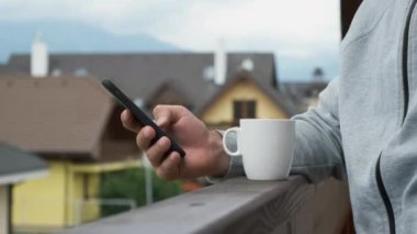 Adam akıllı telefonunu dağların ve yeni evlerin arka planında kullanıyor..