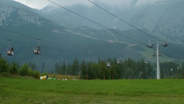Elevadores de esqui móveis ou funiculares no fundo de altas montanhas rochosas. Tempo nublado e ventoso nas montanhas. Trisma de verão ou outono. — Vídeo de Stock