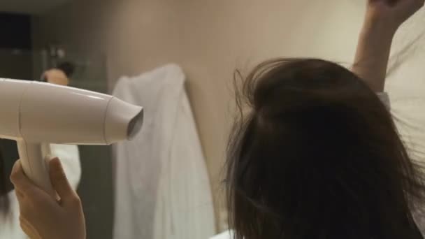 Fermer femme séchage des cheveux avec un sèche-cheveux et brossage avec une brosse ronde dans la salle de bain — Video