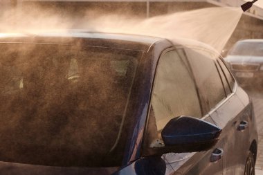 Yüksek basınçlı su kullanarak elle araba yıkama. Gün ışığında temizlik otomobilinin yan görünümü. 