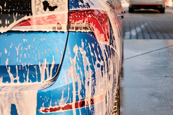 Chiuda un faro in un sapone durante lavaggio di auto con una schiuma. Pulizia di un'auto con acqua ad alta pressione. — Foto Stock