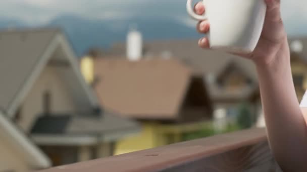 Cerrar una taza blanca tomar arriba y abajo en el balcón con montañas en el fondo — Vídeos de Stock