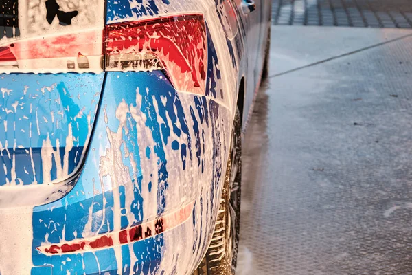 Chiuda un faro in un sapone durante lavaggio di auto con una schiuma. Pulizia di un'auto con acqua ad alta pressione. — Foto Stock