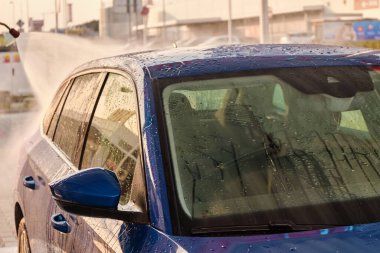 Gün batımında yüksek basınçlı suyun altında araba yıkama. Dışarıda elle araba temizleme sistemi var. self servis araba yıkama konsepti. 