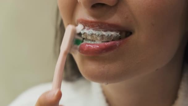 Fermer femme nettoyer les dents avec des accolades avec brosse à dents rose. Supports nettoyage, hygiène dentaire. — Video
