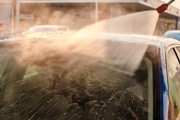 Mycie samochodów pod wysokim ciśnieniem wody o zachodzie słońca. Ręczny system czyszczenia samochodów na zewnątrz. Koncepcja mycia samochodów samoobsługowych. — Zdjęcie stockowe