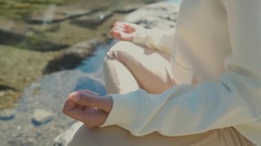 Yakından bir kadın göl kıyısında nilüfer çiçeğiyle yoga yapıyor.. 