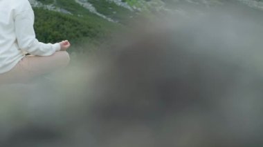 Genç bir kadın göl kıyısında meditasyon yapıyor. Şelale ve dağların manzarası harika.. 