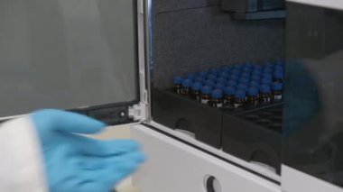Analitik kimyager otomatik HPLC örnekleyicisine bir şişe koyar. Kimya laboratuarında ilaç ve aşı geliştirme. 
