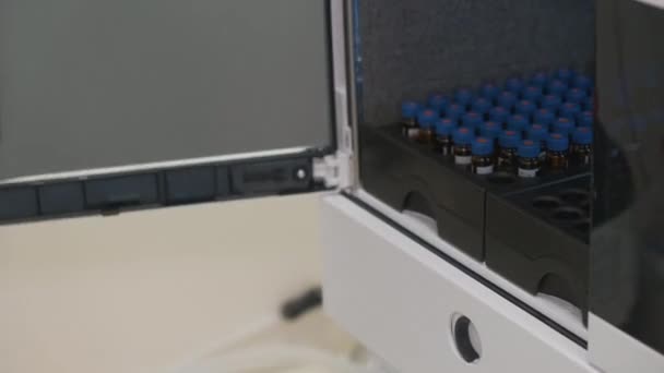 Chimiste analytique met un flacon à l'échantillonneur automatique du système HPLC. — Video