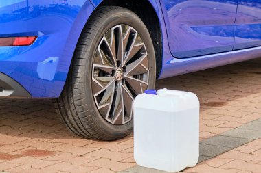 Mavi Skoda otomobilinin direksiyonuna dizel egzoz sıvısı olan beyaz bir teneke kutuyu kapat. Hava kirliliğinin azaltılması için Ad Blue sıvısı, Ekim 2020, Prag, Çek Cumhuriyeti