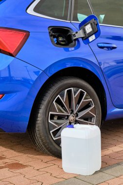 Mavi Skoda otomobilinin direksiyonuna dizel egzoz sıvısı olan beyaz bir teneke kutuyu kapat. Hava kirliliğinin azaltılması için Ad Blue sıvısı, Ekim 2020, Prag, Çek Cumhuriyeti
