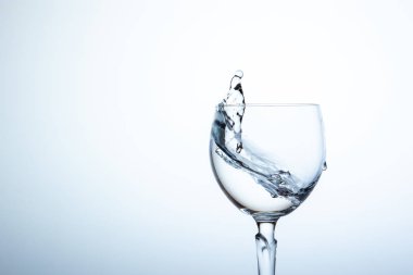 Lüks şarap bardağına su sıçrıyor. Sağlıklı ve ferahlatıcı kavramı. Resmin sol tarafında boşluk kopyala.