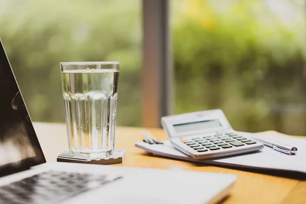 Masadaki bardakta maden içme suyu. Rahatlatıcı bir çalışma ortamı için ev ya da ofis kavramından çalışmak. Sağlık, refah ve iş hayatı dengesi kavramı. Merkez ofis geçmişi.