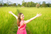 Portré csinos ázsiai lány rózsaszín ruhában élvezi a rizs mező és rét vidéken.