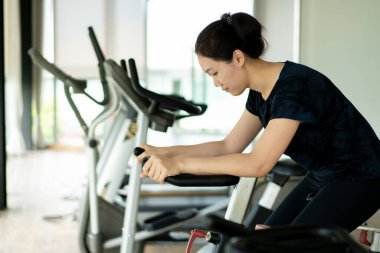 Asyalı kadın egzersiz yapmadan önce kaslarını esnetir. Spor kadını spor salonunda vücut egzersizi ve vücut ağırlığı egzersizi yapıyor. Refah ve refah kavramı.