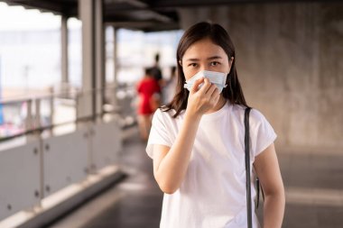 Hava kirliliğiyle dolu olan şehirde seyahat ederken koruyucu maske takan güzel bir Asyalı kadın. Asya 'da sağlıksız kentsel hava kirliliği sorunu ve koronavirüs hastalığı.