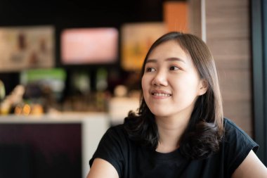 Güzel mutlu Asyalı kadın kafeteryada ve restoranda oturuyor, arka planda bulanık bir telif alanı olan bir kadın. Düşünceli ve yaratıcı kadın kahvecide dinleniyor..