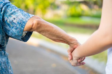 Torun, neredeyse 90 yaşındaki büyükannesine sabah parkta yürüyerek egzersiz yapmasına yardım ediyor. Asyalı bir kadın yaşlı bir kadının yürümesine yardım ediyor. Sağlık, sağlık ve refah..