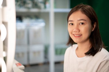 Soyunma odasındaki aynada kendine bakan genç ve güzel Asyalı bir kadın. Yaşlanan kadın kavramında yüz ve cilt bakımı.