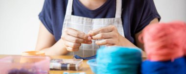 Genç bir kadın boş zamanlarını el işi hobisiyle geçiriyor. Evde otururken örgü ören becerikli bir kadın. Kopya alanı ile ilham ve yaratıcılık çalışma kavramı.