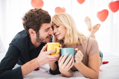 Güzel beyaz bir çift yatak odasındaki kahvaltı setinde birlikte eğleniyor. Kafkasyalı çiftin rahatlama pozu portresi.