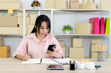 Güzel Asyalı kadın portresi e-ticaret ve online alışveriş konsepti, kadın deftere not yazıyor..