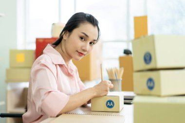 Genç Asyalı iş kadını müşterilere gönderilmek üzere posta kutusu paketliyor. İnternet üzerinden alışveriş konsepti. Çevrimiçi satış uzmanı. Müşterileri paketliyor. Sevkiyat için paket kutuları..