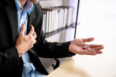 Yaşlı Asyalı işadamının çalışma alışkanlığından dolayı sağlık sorunu var. Acı dolu yaşlı iş adamı kalbinden yaralandı. Ofis semptomları, işkolik insanlarda ofis hastalığı..