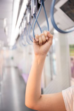 Kadın turist şehir gökyüzü tren sistemi ile şehre seyahat ediyor. Trende tırabzanı tutan kadın fotokopi alanıyla yakın çekim yapıyor. Modern yaşam tarzı konseptinde yalnız kadın turist. Kentsel yaşam tarzı.
