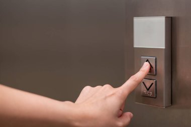 İnsanlar asansördeki düğmeye basıyor ve işaret parmağını kullanarak birinci katı seçiyorlar. Küçük binadaki asansör kontrol paneli. Yolcu asansöründeki düğmede çan alfabesi var..