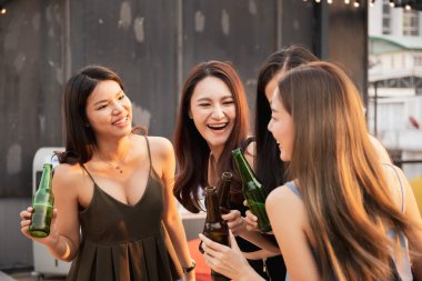 Partide beyaz şarap ve birayla kutlama yapan bir grup insan. Mutlu Asyalılar festivalde eğlenmeyi ve çatıdaki barda ve restoranda beyaz şarapla kutlamayı severler..