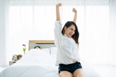 Kocası yatakta mutlu bir şekilde uyurken karısı erkenden uyanıp esniyor. Yatak odasında yatan karı koca arasındaki ilişki ve birlikteliğin mutluluğu. Rahatlama ve refah yaşam tarzı