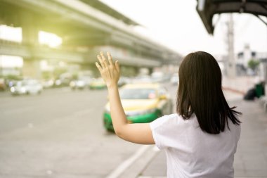 Asyalı turist taksi şoförüyle randevu almak için akıllı telefondan taksi başvurusu yapıyor. Akıllı telefon kullanarak taksi şoförü arayan bir kadın. Copyspace ile modern kentsel ulaşım kavramı.