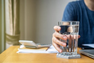 Masadaki bardakta maden içme suyu. Rahatlatıcı bir çalışma ortamı için ev ya da ofis kavramından çalışmak. Sağlık, refah ve iş hayatı dengesi kavramı. Merkez ofis geçmişi.