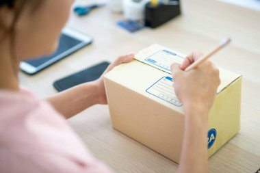 Genç Asyalı iş kadını müşterilere gönderilmek üzere posta kutusu paketliyor. İnternet üzerinden alışveriş konsepti. Çevrimiçi satış uzmanı. Müşterileri paketliyor. Sevkiyat için paket kutuları..