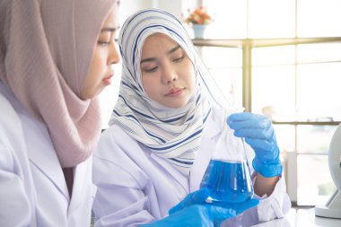 Genç Asyalı Müslüman kadın laboratuvarda kimya deneyi yapıyor. Laboratuvar konseptinde kadın müslüman bilim adamı..