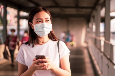 Hava kirliliğiyle dolu olan şehirde seyahat ederken koruyucu maske takan güzel bir Asyalı kadın. Asya 'da sağlıksız kentsel hava kirliliği sorunu ve koronavirüs hastalığı.