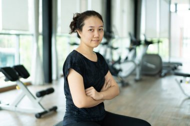 Asyalı şişman kadın kapalı spor salonunda bisiklet antrenmanı yapıyor. Bisiklet makinesiyle kişisel egzersiz yapan bir kadın. Kadın vücudunda bakım ve refah. Spor salonunda spor yapan neşeli şişman kadın..