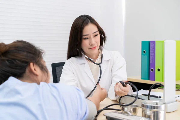 Beautiful Asian doctor checking blood pressure of unhealthy fat woman.  Health care and wellness concept.