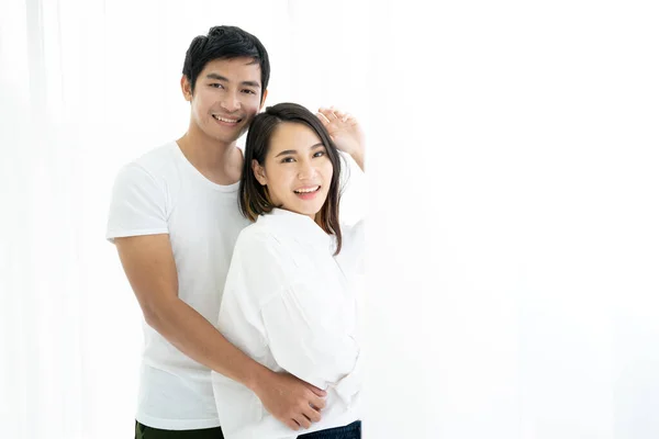 Asian young couple\'s portrait, a couple standing and talking near the window in the morning.