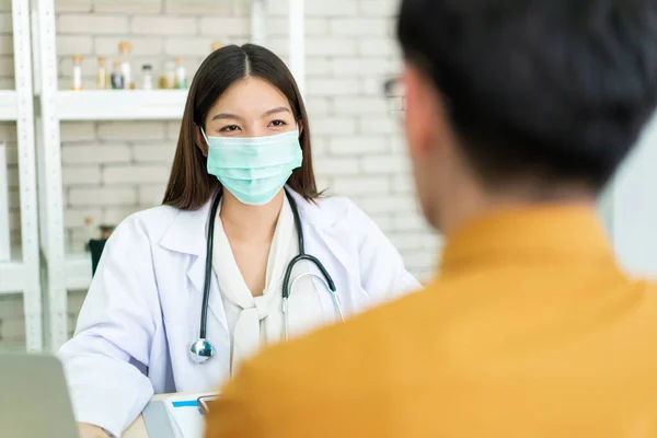 Asian specialist doctor talking to a patient in doctor office in hospital. Patient worried about his sickness and influenza come to a doctor and taking examination in hospital. Healthcare concept.