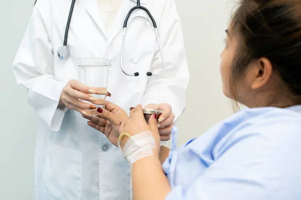 Asyalı şişman kadın doktordan su ve ilaç alıyor. Modern yaşam tarzında sağlık ve sağlıklı beslenme kavramı.