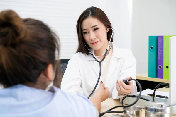 Güzel Asyalı doktor sağlıksız şişman kadının kan basıncını ölçüyor. Sağlık ve Sağlık Konsepti.