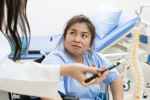 Asyalı şişman kadın hasta hastanedeki uzman doktorla sağlık hastalığı hakkında konuşuyor. Kadın omurgasındaki kritik sorun için endişeleniyor. Aşırı kilolu olması fiziksel yaralanmaya neden olabilir..