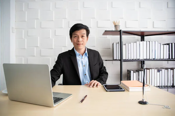 アジアの高齢者のビジネスマン 60歳のオフィスで働いています 職場にはアジア系のシニアディレクターの肖像画が飾られている 最高経営責任者 Ceo オフィスの彼の個人的な部屋で — ストック写真