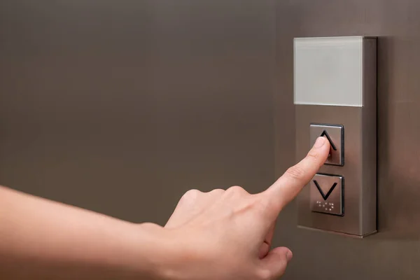 People pressing the button in the lift and select the first floor by using the forefinger. Elevator control panel in small building close up. Bell alphabet on the button in the passenger lift.