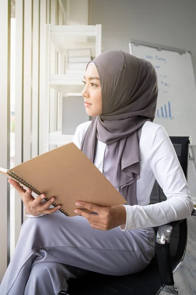 アジア系ムスリム女性がオフィスで本を読んでいます 現代のイスラム教徒のライフスタイルの概念 イスラム教徒の肖像 — ストック写真