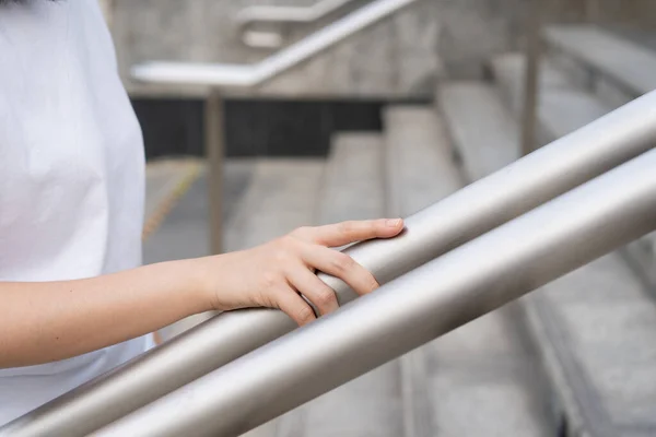 여자가 계단을 걷다가 난간을 잡았어요 가까이 난간을 잡는다 계단을 걷다가 — 스톡 사진